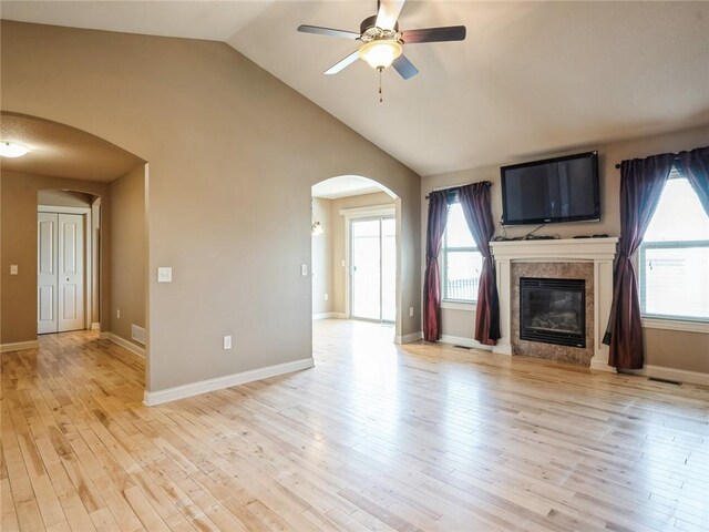 unfurnished living room with high vaulted ceiling, light wood-type flooring, and ceiling fan