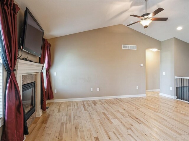 unfurnished living room featuring vaulted ceiling, a fireplace, ceiling fan, and light hardwood / wood-style floors