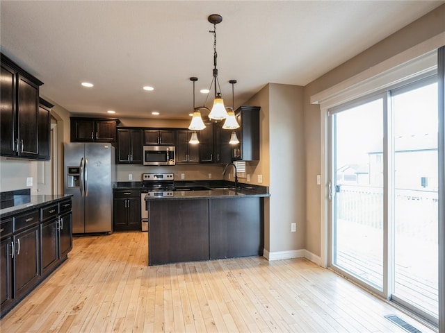 kitchen featuring stainless steel appliances, a wealth of natural light, light wood-type flooring, and pendant lighting