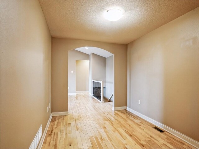 empty room featuring light wood-type flooring and a textured ceiling