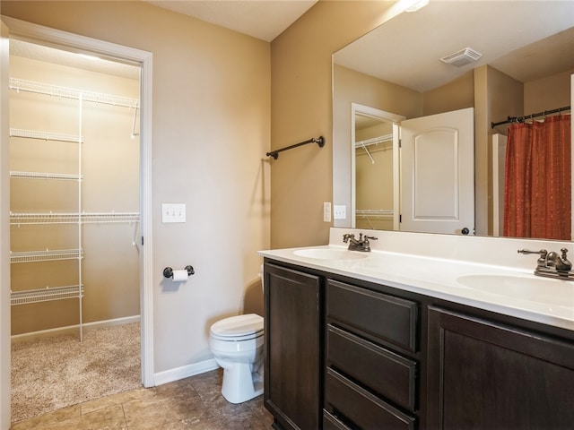 bathroom featuring tile patterned floors, toilet, and dual bowl vanity