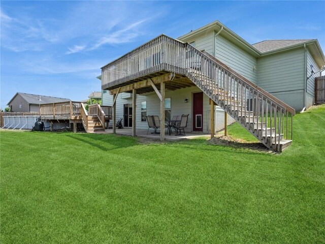 back of property with a patio, a wooden deck, and a lawn