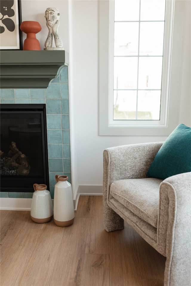 living area featuring a tile fireplace and wood-type flooring