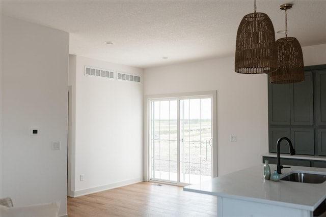 127 N 36th St, Cumming, IA 50061 - kitchen with a sink, light countertops, light wood-style floors, and baseboards