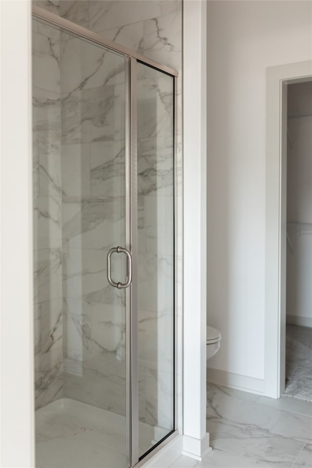 bathroom featuring toilet and a shower with door