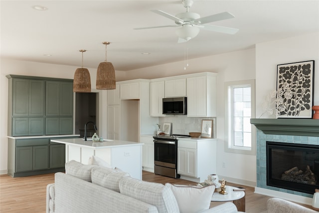 kitchen featuring a kitchen island with sink, light hardwood / wood-style flooring, decorative backsplash, decorative light fixtures, and stainless steel appliances