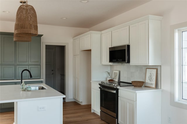 127 N 36th St, Cumming, IA 50061 - kitchen featuring stainless steel appliances, a sink, tasteful backsplash, light countertops, and wood finished floors