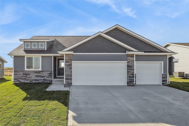 craftsman house with an attached garage, stone siding, a front yard, cooling unit, and driveway