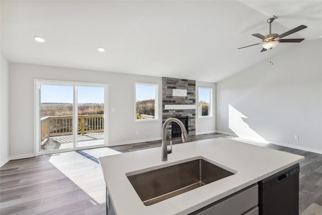 kitchen featuring a fireplace, open floor plan, light countertops, a sink, and dishwasher