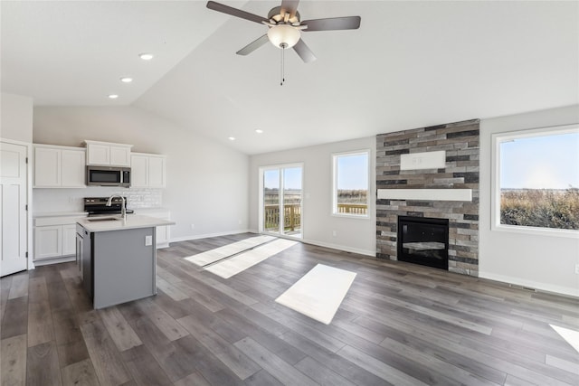 kitchen featuring appliances with stainless steel finishes, vaulted ceiling, a sink, light countertops, and open floor plan