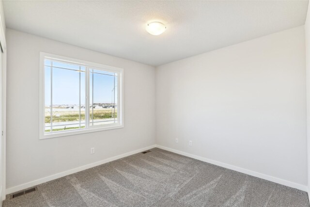 carpeted empty room featuring visible vents and baseboards