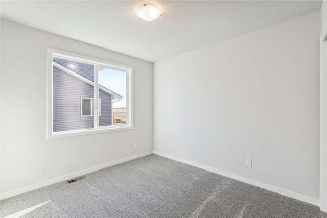 carpeted spare room with visible vents and baseboards