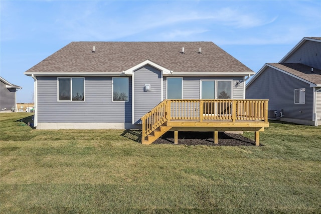 rear view of house featuring central air condition unit, a shingled roof, a wooden deck, and a yard