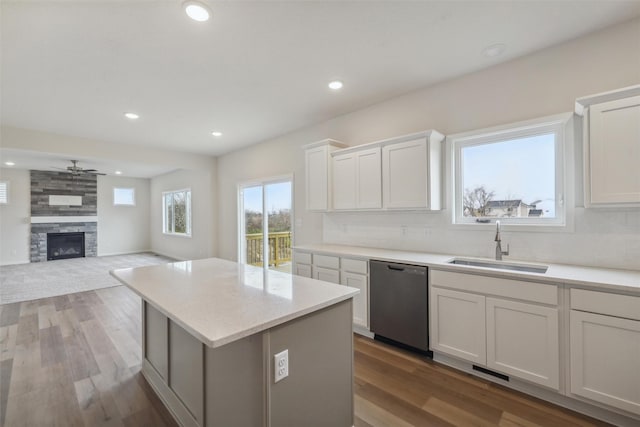 kitchen featuring hardwood / wood-style flooring, dishwasher, white cabinetry, and a fireplace