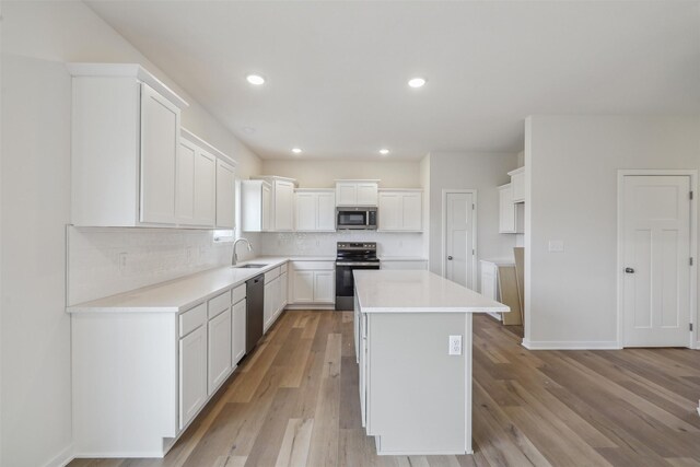 kitchen with a center island, sink, light hardwood / wood-style floors, white cabinets, and appliances with stainless steel finishes