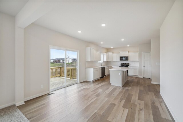 kitchen with white cabinets, a center island, stainless steel appliances, and light hardwood / wood-style floors