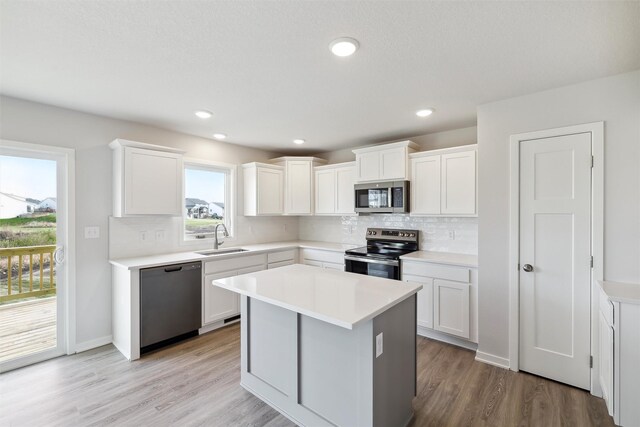 kitchen featuring appliances with stainless steel finishes, light wood-type flooring, white cabinetry, and sink