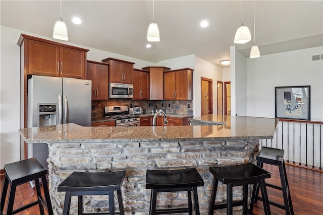 kitchen featuring tasteful backsplash, hanging light fixtures, appliances with stainless steel finishes, and a breakfast bar area