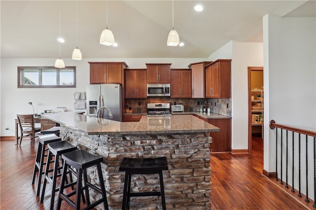 kitchen with a kitchen breakfast bar, decorative backsplash, stainless steel appliances, and decorative light fixtures