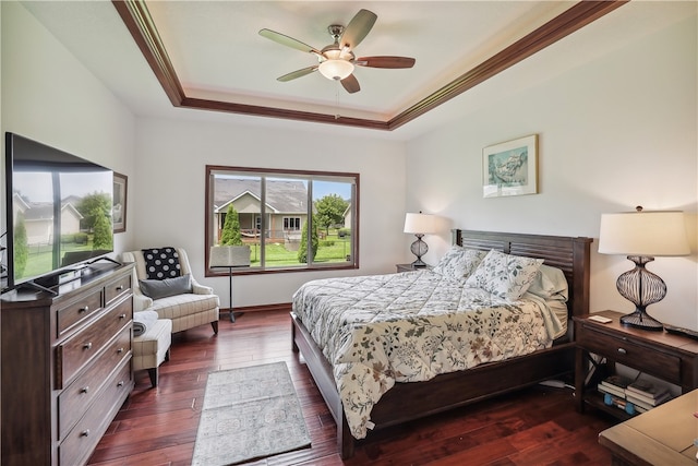 bedroom featuring a tray ceiling, crown molding, ceiling fan, and dark wood-type flooring