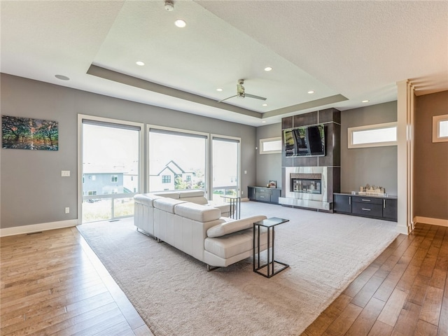 living room with hardwood / wood-style floors, a raised ceiling, and a wealth of natural light