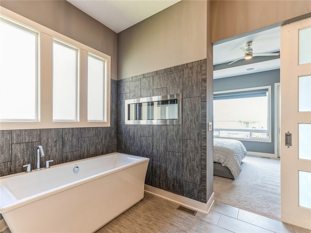 bathroom featuring tile patterned floors, ceiling fan, and a tub to relax in