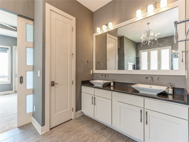 bathroom with an inviting chandelier, tile patterned flooring, and double sink vanity