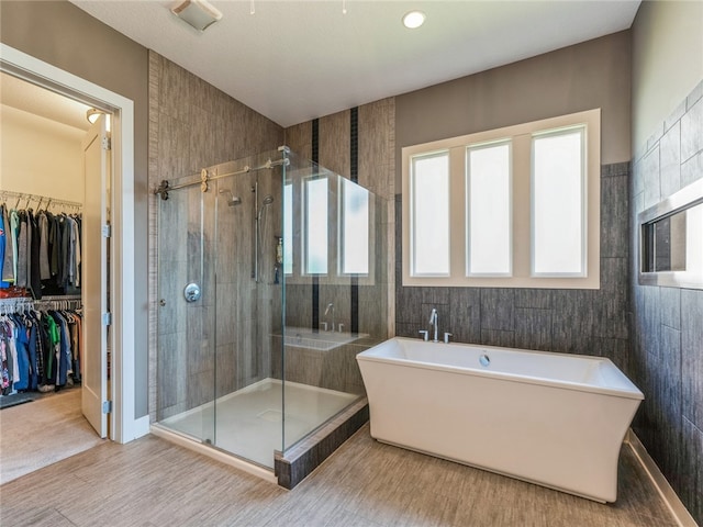 bathroom featuring shower with separate bathtub, tile patterned floors, and tile walls