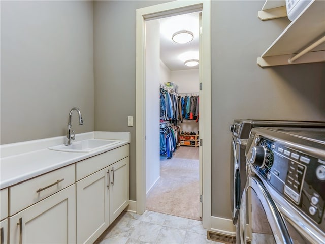 laundry area featuring washing machine and clothes dryer, sink, cabinets, and light tile patterned floors