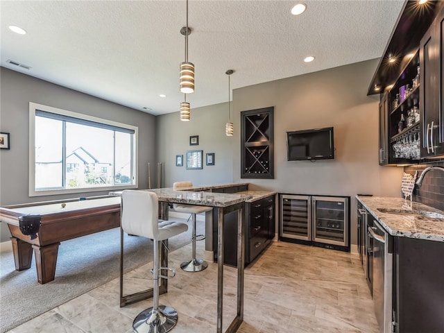 interior space with light tile patterned flooring, billiards, hanging light fixtures, sink, and light stone countertops