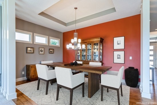 dining room featuring a notable chandelier, wood-type flooring, and a raised ceiling