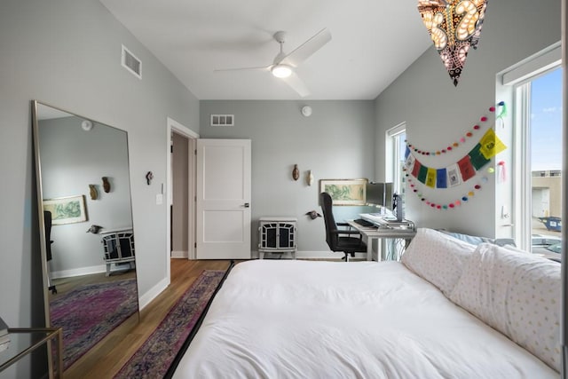 bedroom with dark hardwood / wood-style flooring and ceiling fan with notable chandelier