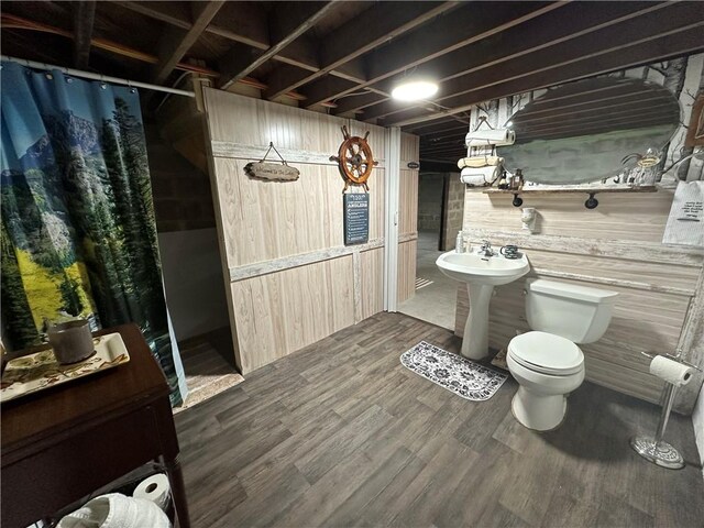 bathroom featuring wood walls, wood-type flooring, and toilet