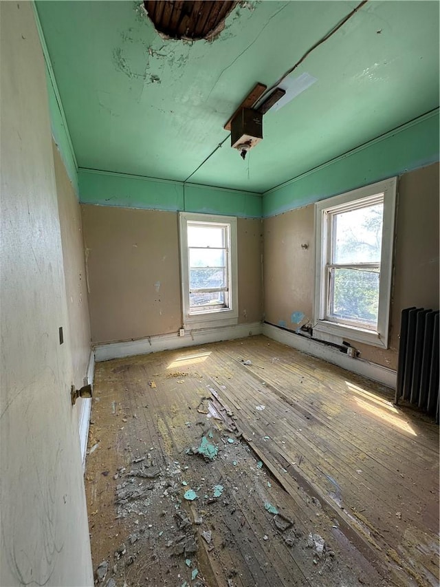 1427 5th Ave, Des Moines, IA 50314 - spare room with radiator and hardwood / wood-style flooring