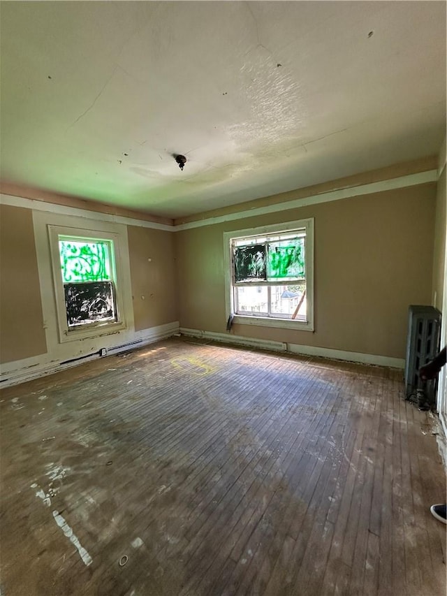 1427 5th Ave, Des Moines, IA 50314 - unfurnished living room featuring baseboards, plenty of natural light, and hardwood / wood-style floors