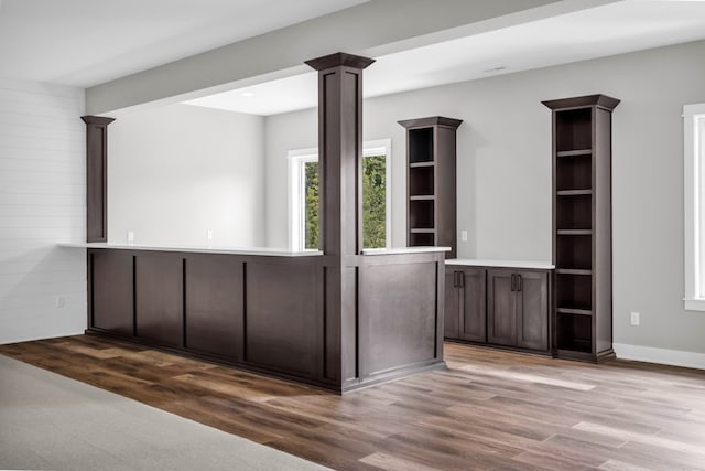 interior space featuring dark brown cabinets, light wood-type flooring, and ornate columns