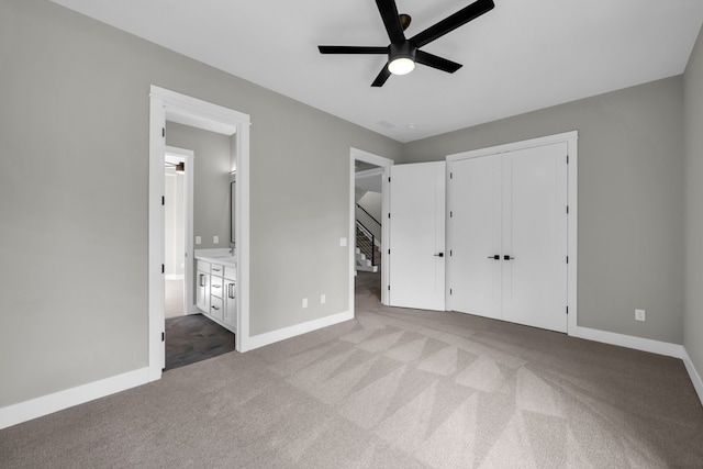 unfurnished bedroom featuring ensuite bath, a closet, carpet floors, and ceiling fan