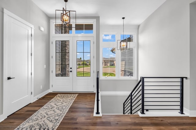 foyer entrance with dark wood-type flooring, french doors, and an inviting chandelier