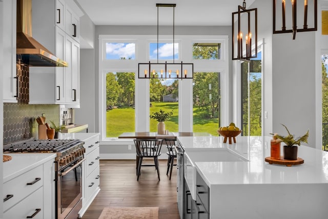 kitchen with dark hardwood / wood-style floors, high end stainless steel range oven, hanging light fixtures, and wall chimney exhaust hood