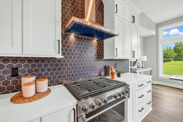 kitchen featuring tasteful backsplash, high end stainless steel range oven, light hardwood / wood-style flooring, and wall chimney exhaust hood