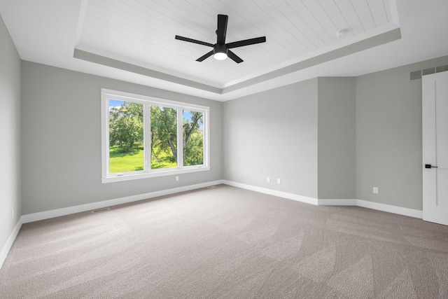 carpeted empty room featuring ceiling fan and a raised ceiling