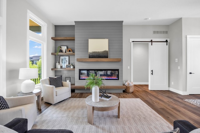 living room with a barn door, a fireplace, and hardwood / wood-style floors