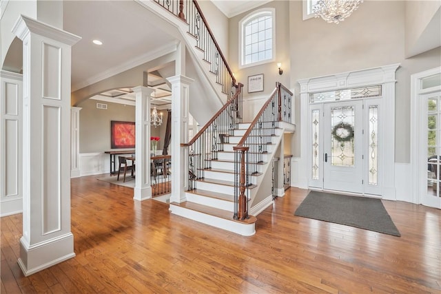4701 150th St, Urbandale, IA 50323 - entryway featuring decorative columns, a chandelier, a decorative wall, wood-type flooring, and wainscoting