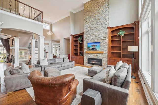 4701 150th St, Urbandale, IA 50323 - living area featuring decorative columns, ornamental molding, a towering ceiling, plenty of natural light, and wood finished floors