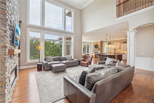 4701 150th St, Urbandale, IA 50323 - living room featuring arched walkways, a towering ceiling, light wood finished floors, plenty of natural light, and ornamental molding