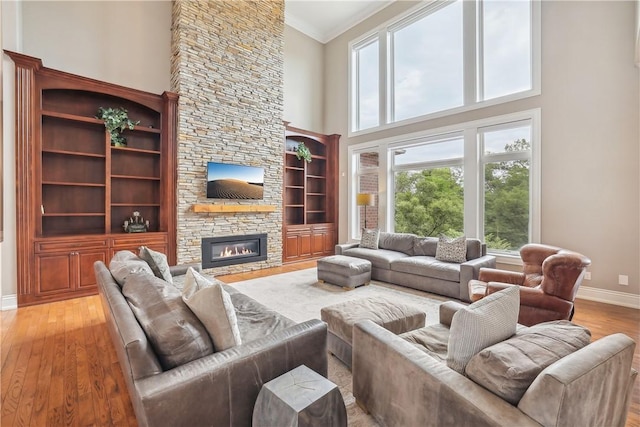 4701 150th St, Urbandale, IA 50323 - living area with baseboards, a high ceiling, light wood-style flooring, a stone fireplace, and ornamental molding