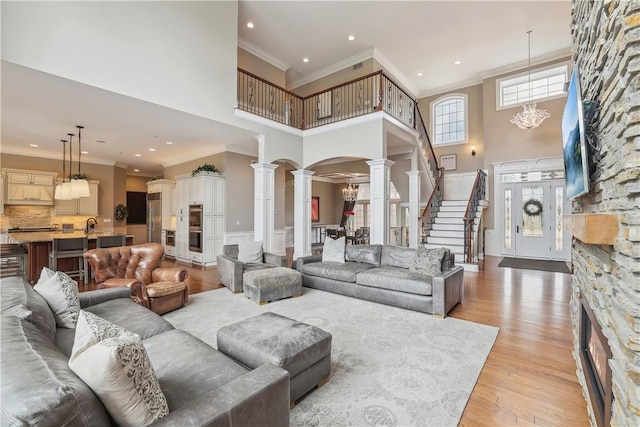 4701 150th St, Urbandale, IA 50323 - living area featuring decorative columns, a high ceiling, crown molding, light wood-style floors, and recessed lighting