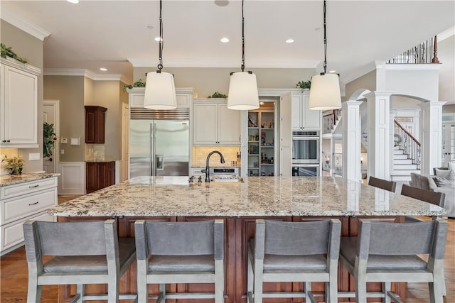 4701 150th St, Urbandale, IA 50323 - kitchen with appliances with stainless steel finishes, a sink, ornate columns, ornamental molding, and recessed lighting