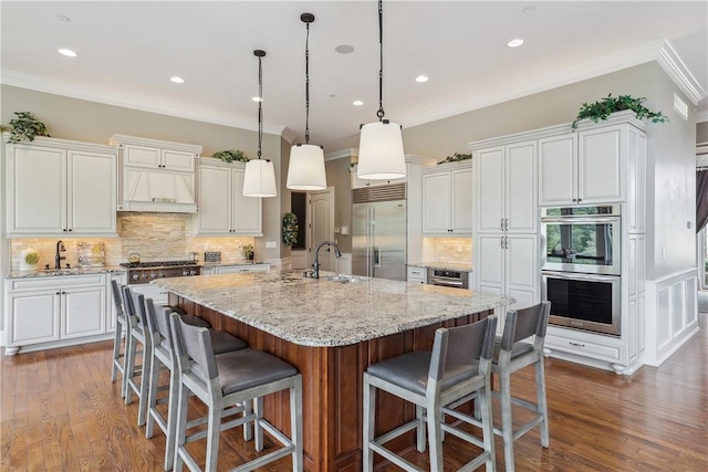 4701 150th St, Urbandale, IA 50323 - kitchen with appliances with stainless steel finishes, a sink, white cabinets, decorative backsplash, and a spacious island