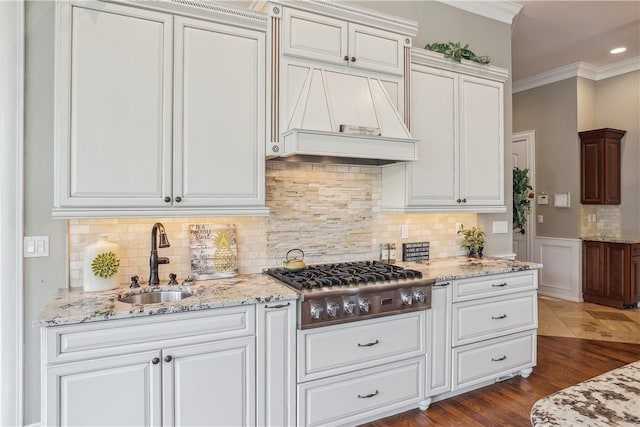 4701 150th St, Urbandale, IA 50323 - kitchen with stainless steel gas stovetop, a sink, custom range hood, light stone countertops, and crown molding